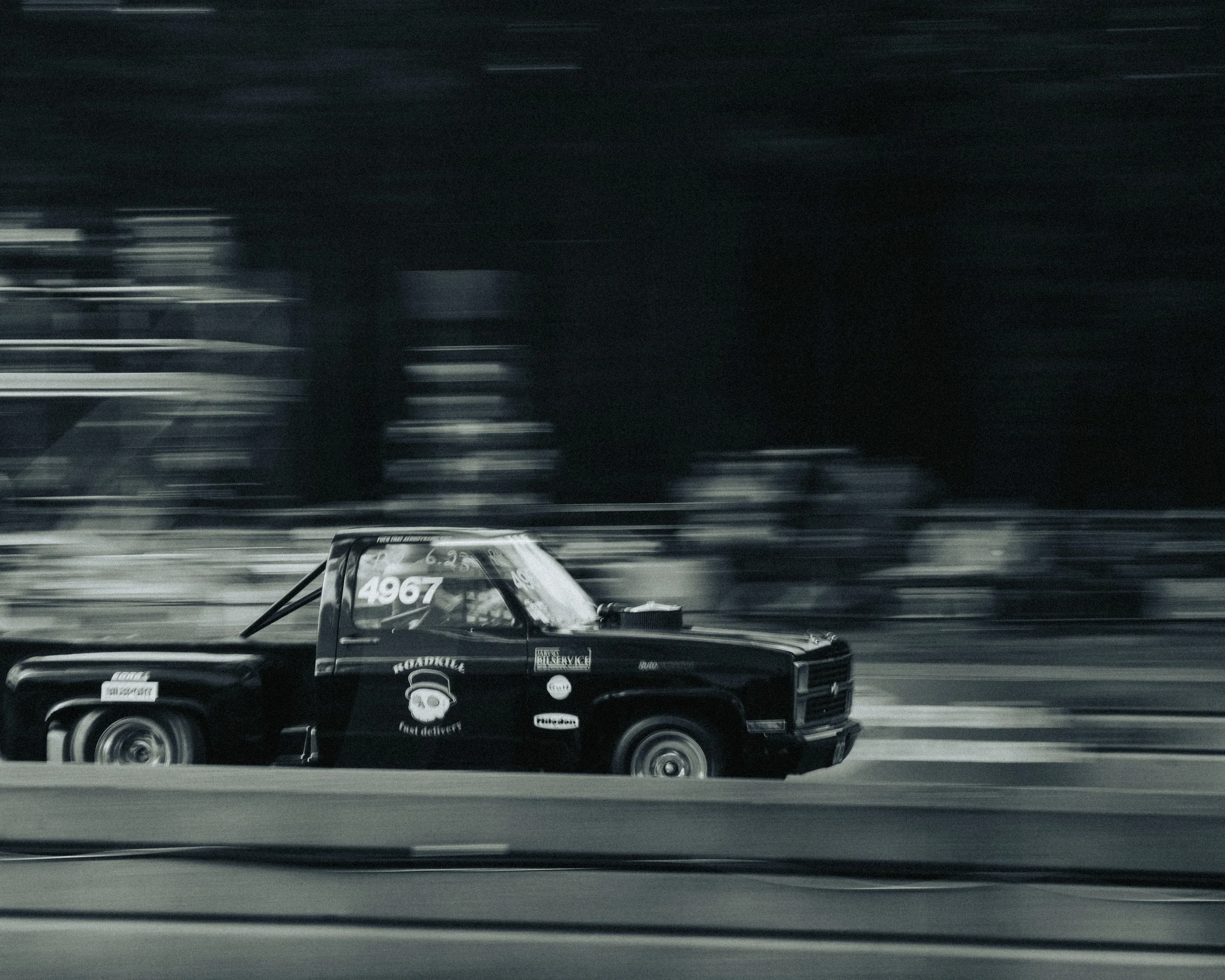 Panning shot of a black vintage pickup truck racing past