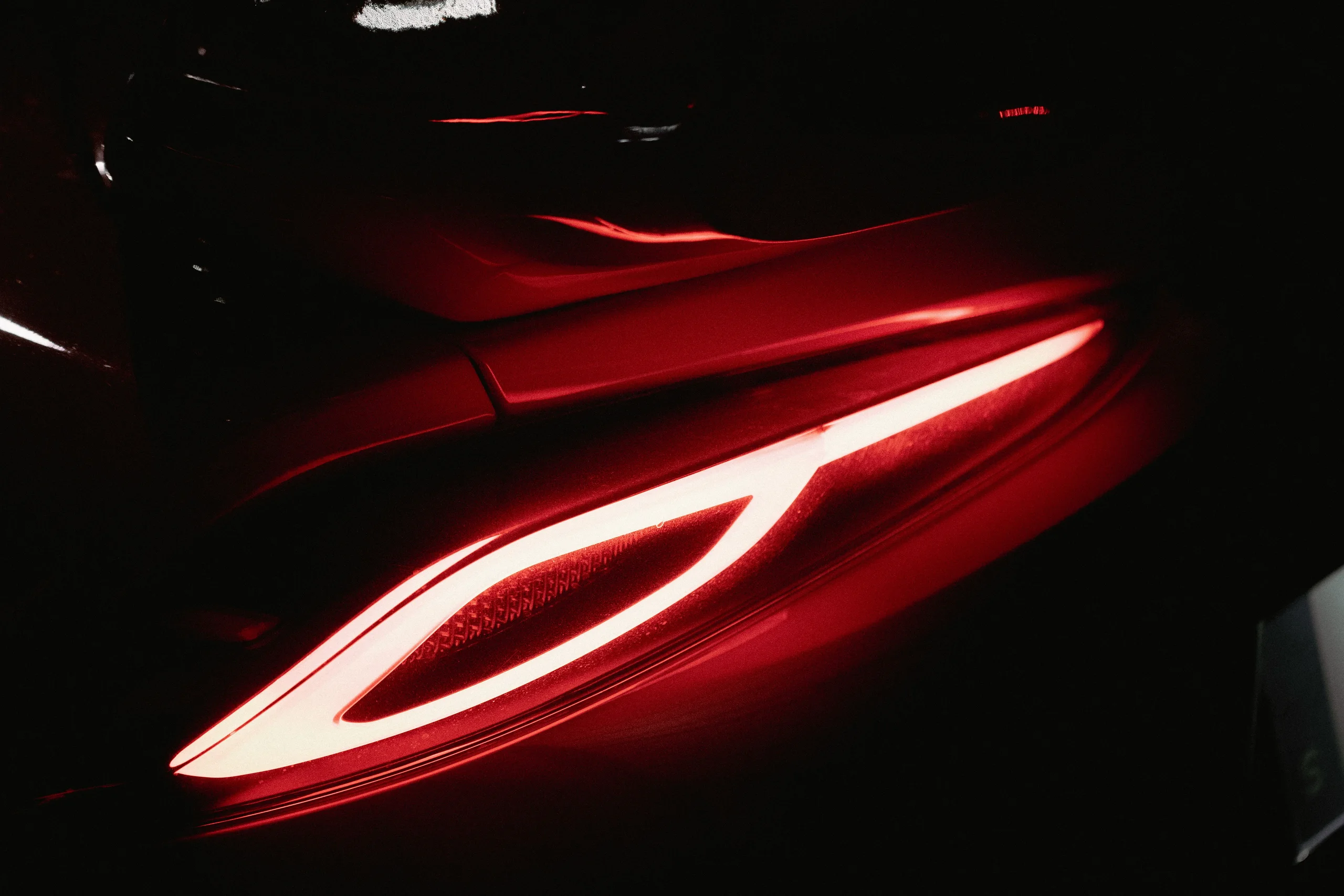 Glowing red tail light of a car in darkness
